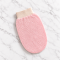 Pink exfoliating glove on clean white marble surface