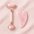 Pink facial roller and gua sha set on blush linen surface